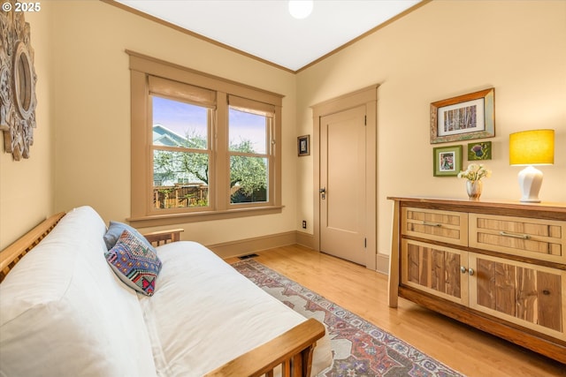 interior space featuring baseboards, visible vents, ornamental molding, and light wood finished floors