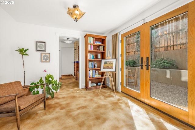 living area featuring french doors, baseboards, and light colored carpet