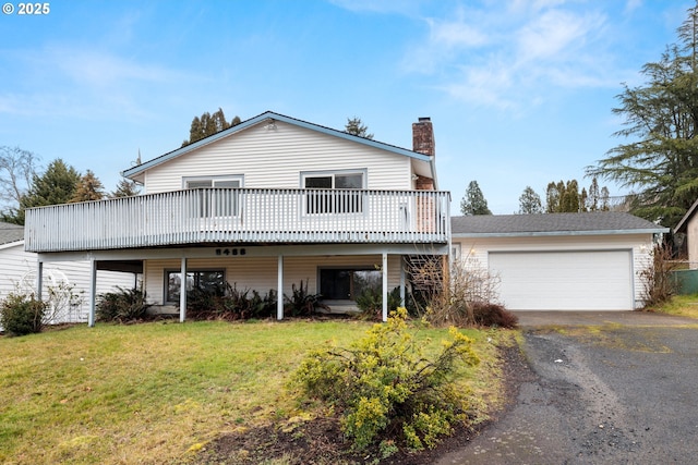 front facade featuring a wooden deck, a garage, and a front yard