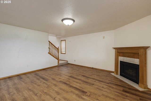 2907 NE 166th Pl, Vancouver, WA 98682 - unfurnished living room with wood finished floors, stairway, a tile fireplace, baseboards, and a textured ceiling