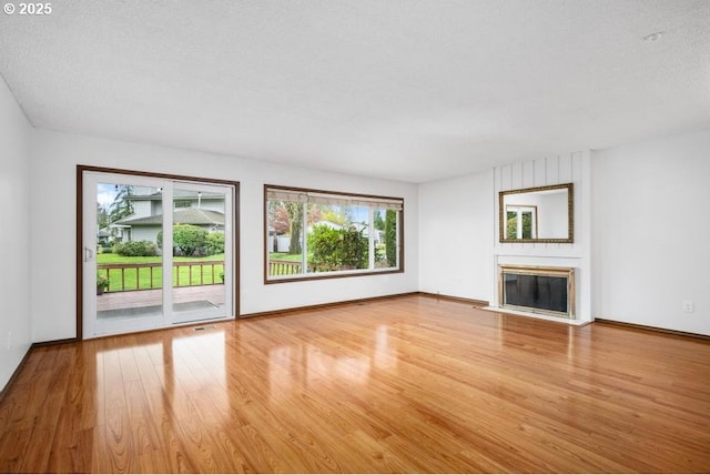 9998 SW French Prairie Rd, Wilsonville, OR 97070 - unfurnished living room with a large fireplace, baseboards, and wood finished floors