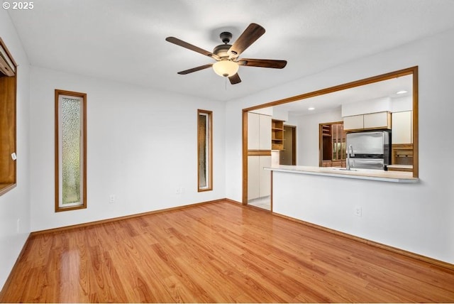 9998 SW French Prairie Rd, Wilsonville, OR 97070 - unfurnished living room featuring light wood-style floors, baseboards, and a ceiling fan