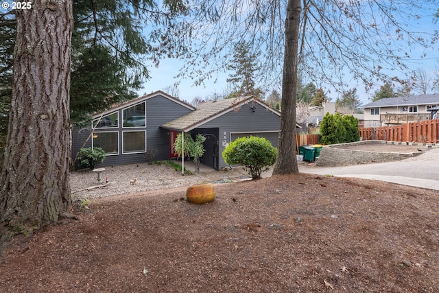 mid-century inspired home featuring an attached garage and fence