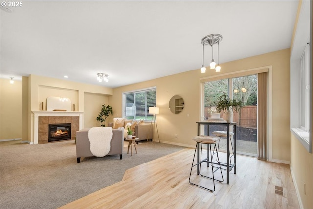 dining space featuring light carpet, visible vents, baseboards, and a tile fireplace