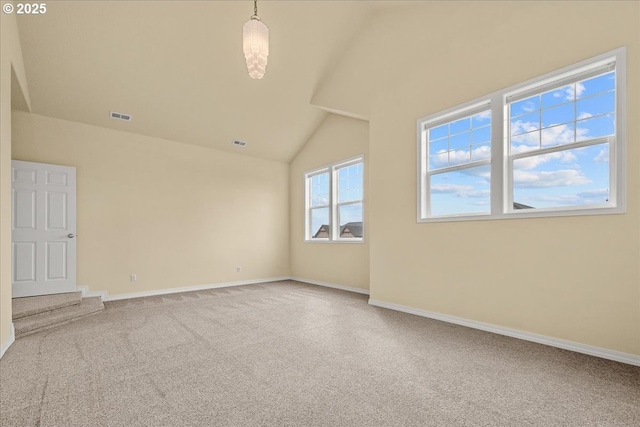 carpeted spare room featuring visible vents, baseboards, and lofted ceiling