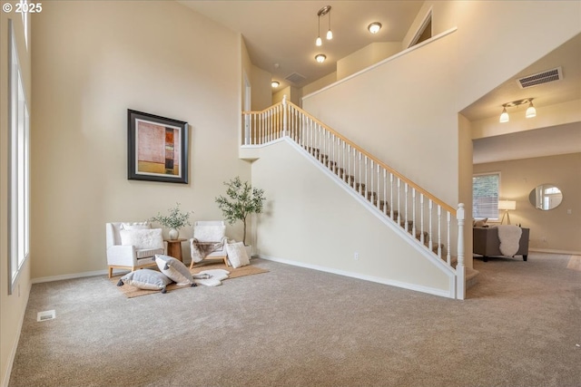 sitting room featuring stairs, carpet, visible vents, and a towering ceiling