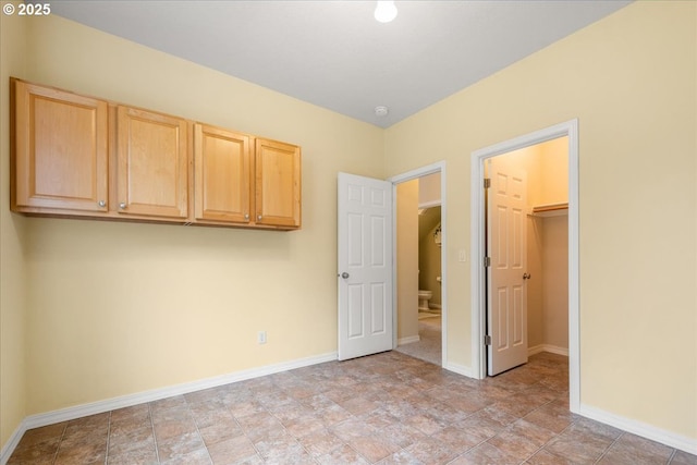 unfurnished bedroom featuring a walk in closet and baseboards