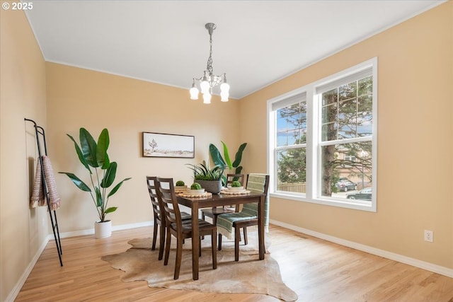 dining room featuring a notable chandelier, light wood-type flooring, and baseboards