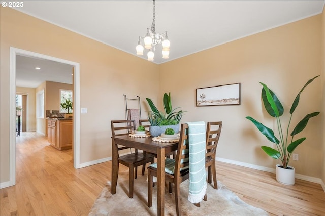 dining room featuring baseboards, a chandelier, and light wood finished floors