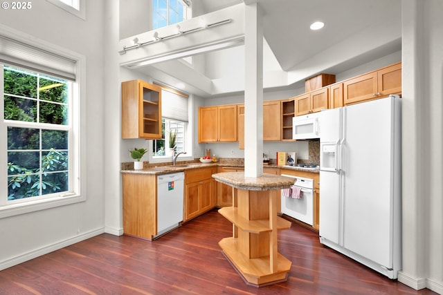 kitchen with sink, white appliances, a center island, light stone countertops, and dark hardwood / wood-style flooring