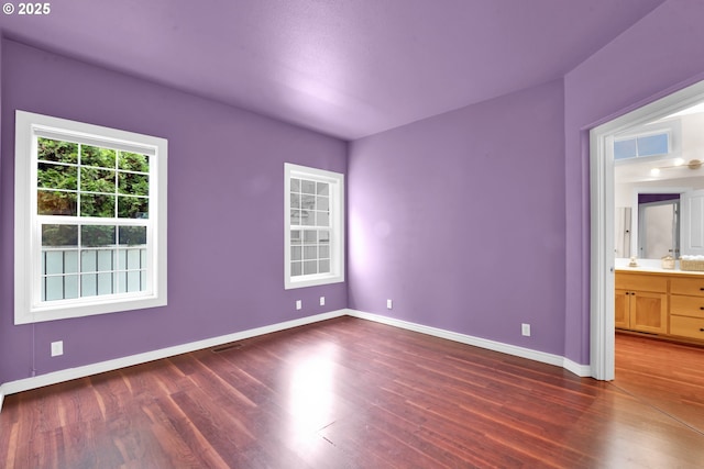 unfurnished bedroom with connected bathroom and dark hardwood / wood-style floors