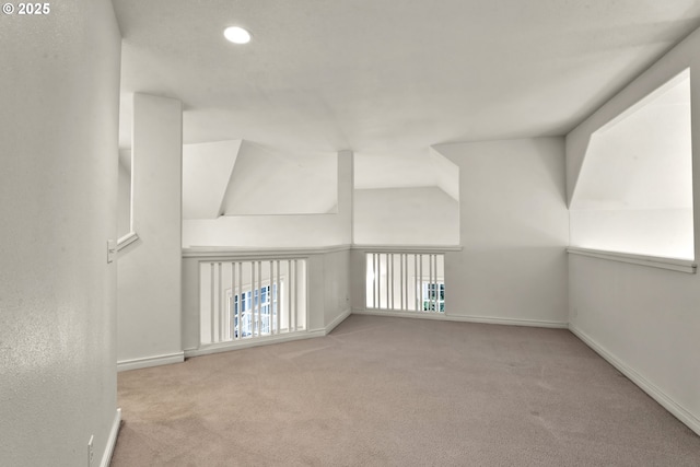 additional living space with light colored carpet and vaulted ceiling