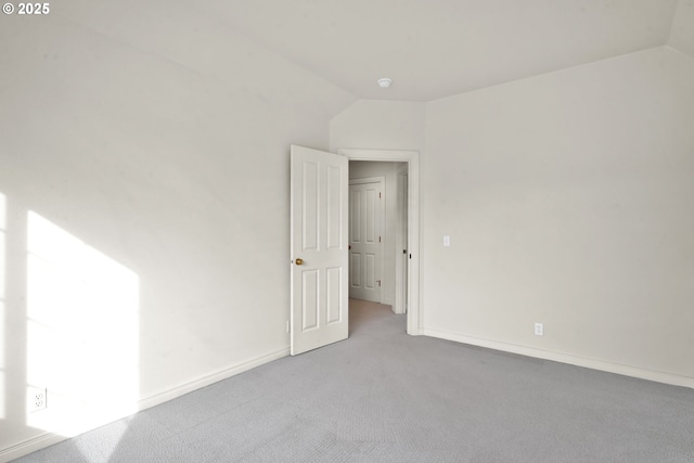 carpeted empty room featuring lofted ceiling