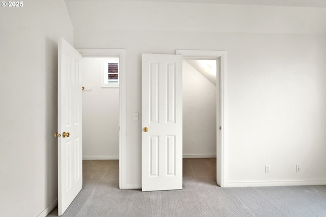 unfurnished bedroom featuring a spacious closet and light colored carpet