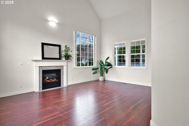 unfurnished living room with a tile fireplace, high vaulted ceiling, and dark hardwood / wood-style flooring