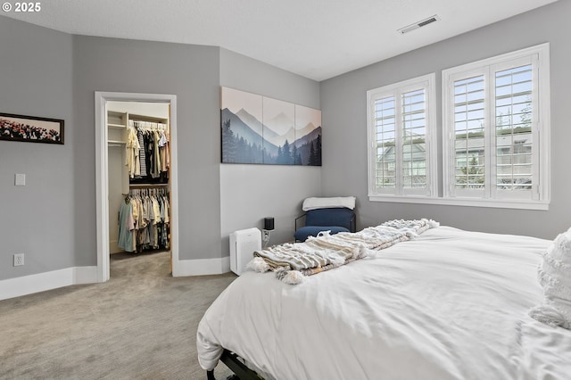 bedroom featuring a walk in closet, light carpet, and a closet