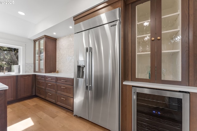 kitchen with stainless steel built in fridge, wine cooler, light countertops, and a sink