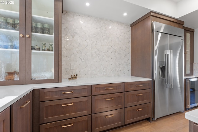 kitchen featuring light wood-style floors, beverage cooler, glass insert cabinets, and built in fridge