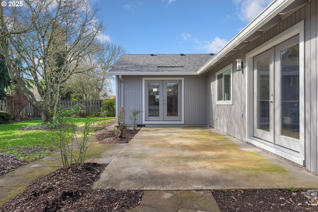 property entrance featuring a shingled roof, fence, a patio, and french doors