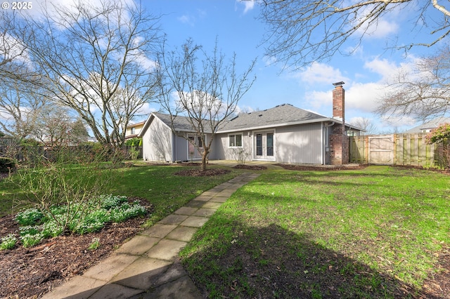 back of property with french doors, a fenced backyard, a lawn, and a chimney