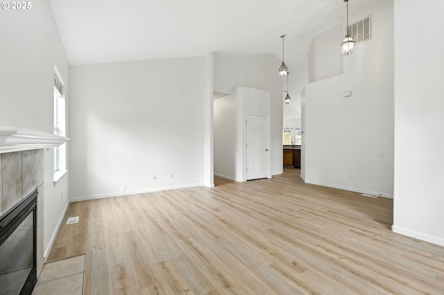 59673 Oak Ridge St, Saint Helens, OR 97051 - unfurnished living room with a tile fireplace, healthy amount of natural light, high vaulted ceiling, and light wood-style flooring