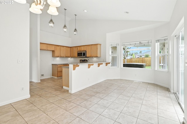59673 Oak Ridge St, Saint Helens, OR 97051 - kitchen with stainless steel microwave, light tile patterned flooring, high vaulted ceiling, light countertops, and a peninsula
