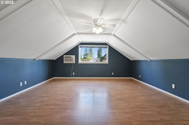 bonus room featuring a ceiling fan, wood finished floors, vaulted ceiling, baseboards, and an AC wall unit