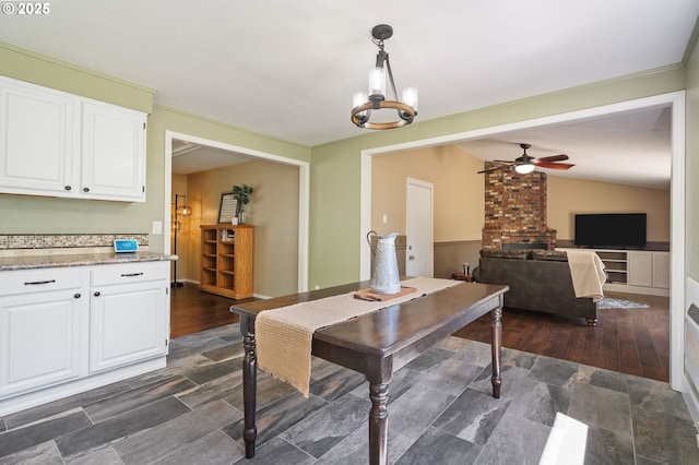 dining area with a ceiling fan, a chandelier, and vaulted ceiling