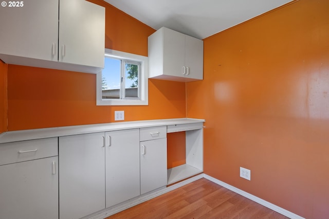 kitchen featuring white cabinetry, light countertops, light wood finished floors, and baseboards