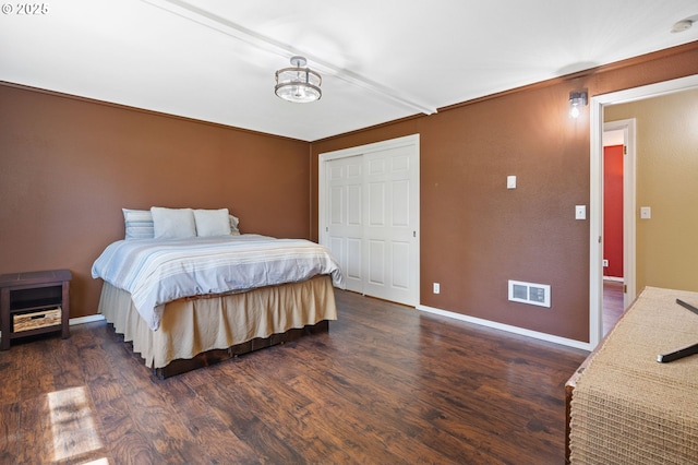 bedroom featuring dark wood-style flooring, baseboards, and a closet