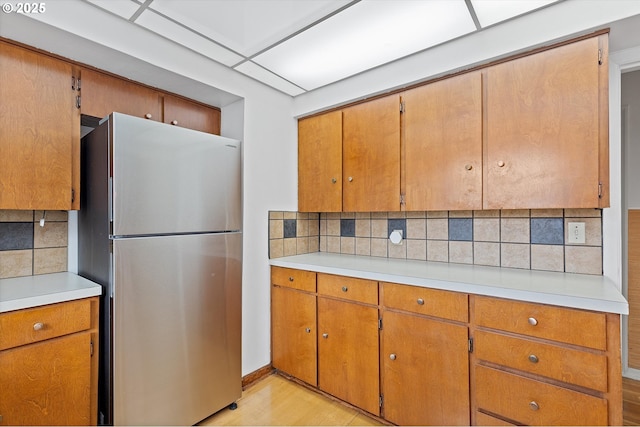 kitchen with tasteful backsplash, stainless steel fridge, and light wood-type flooring