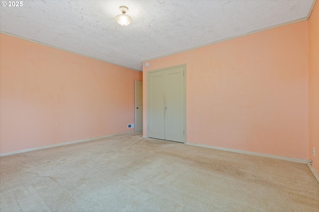 unfurnished room featuring light carpet and a textured ceiling