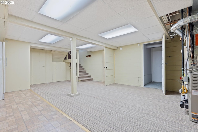 basement with a paneled ceiling and light colored carpet