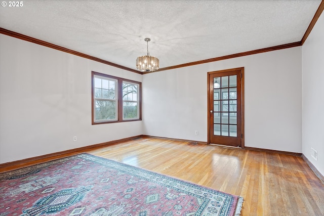 spare room featuring a healthy amount of sunlight, a notable chandelier, a textured ceiling, and light hardwood / wood-style flooring