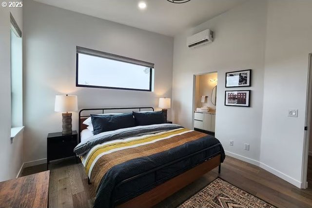 280 NW Huckleberry St, Waldport, OR 97394 - bedroom with a wall mounted air conditioner, wood finished floors, baseboards, recessed lighting, and ensuite bathroom