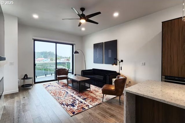 280 NW Huckleberry St, Waldport, OR 97394 - living area featuring wood finished floors, ceiling fan, recessed lighting, baseboards, and a fireplace