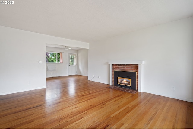 10438 NE Davis St, Portland, OR 97220 - unfurnished living room featuring light wood-type flooring, a brick fireplace, ceiling fan, and baseboards