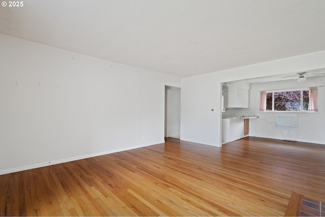 10438 NE Davis St, Portland, OR 97220 - unfurnished living room featuring light wood-style floors, a ceiling fan, and baseboards