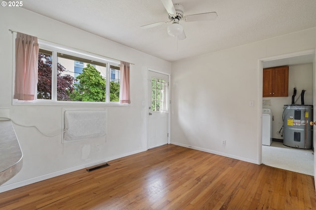 10438 NE Davis St, Portland, OR 97220 - spare room with electric water heater, washer / clothes dryer, light wood-type flooring, a ceiling fan, and baseboards