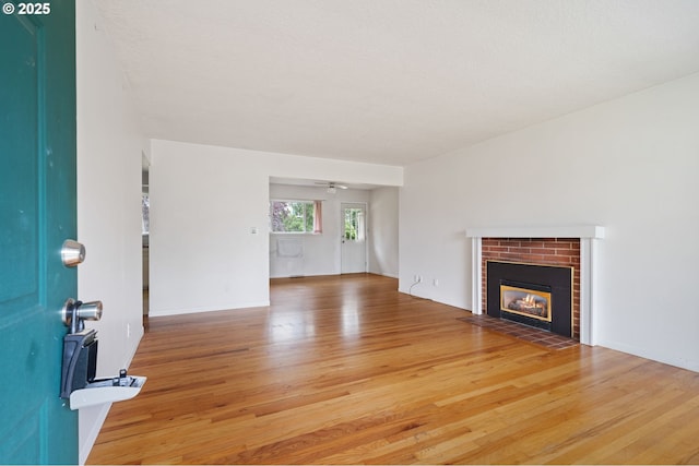 10438 NE Davis St, Portland, OR 97220 - unfurnished living room featuring wood finished floors, a brick fireplace, a ceiling fan, and baseboards