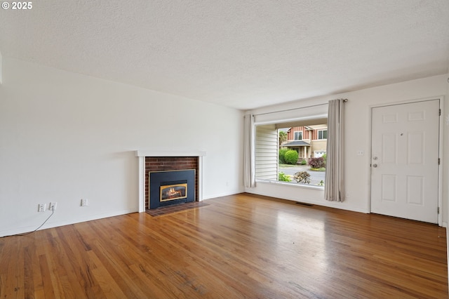 10438 NE Davis St, Portland, OR 97220 - unfurnished living room featuring a textured ceiling, wood finished floors, a brick fireplace, and baseboards