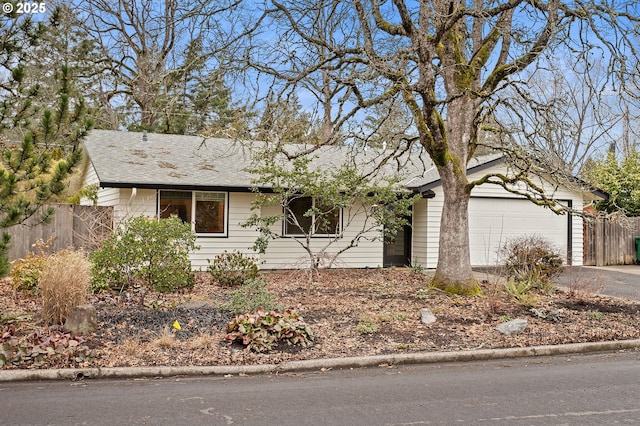 single story home featuring a garage, driveway, and fence