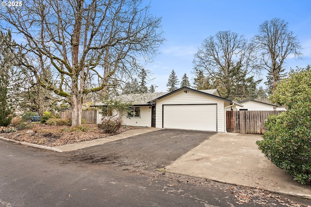 ranch-style home with an attached garage, driveway, and fence