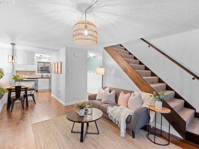 living room featuring a textured ceiling, light hardwood / wood-style floors, and sink