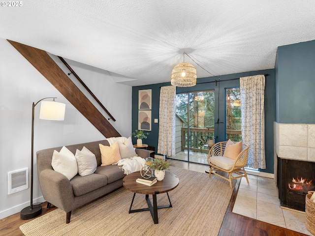 living room with a tiled fireplace, light hardwood / wood-style flooring, and a textured ceiling