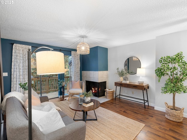 living room featuring a textured ceiling, dark hardwood / wood-style flooring, and a tiled fireplace