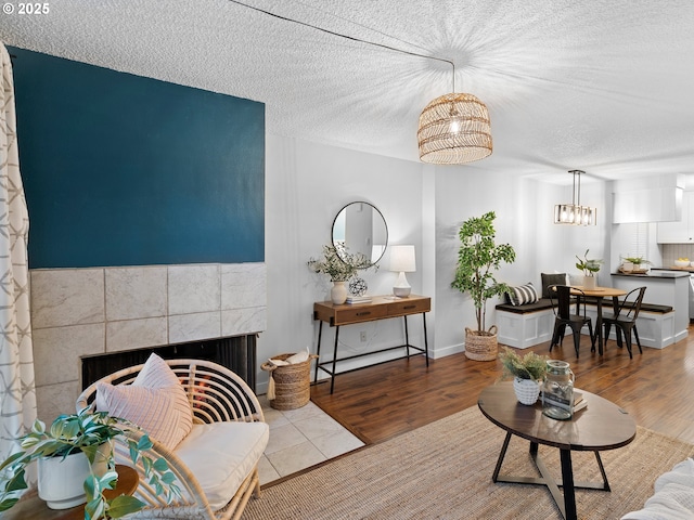 living room featuring wood-type flooring, a textured ceiling, and a tile fireplace