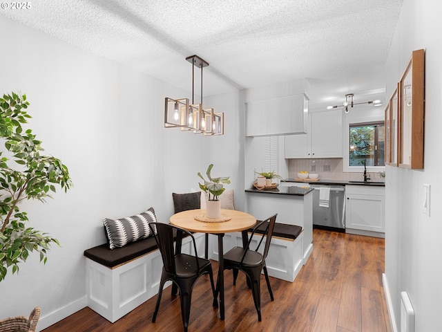 dining space with a textured ceiling, sink, and dark hardwood / wood-style floors