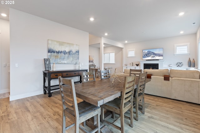 16679 SW Darwin Loop, Portland, OR 97224 - dining room featuring light wood-style flooring, recessed lighting, a glass covered fireplace, and baseboards