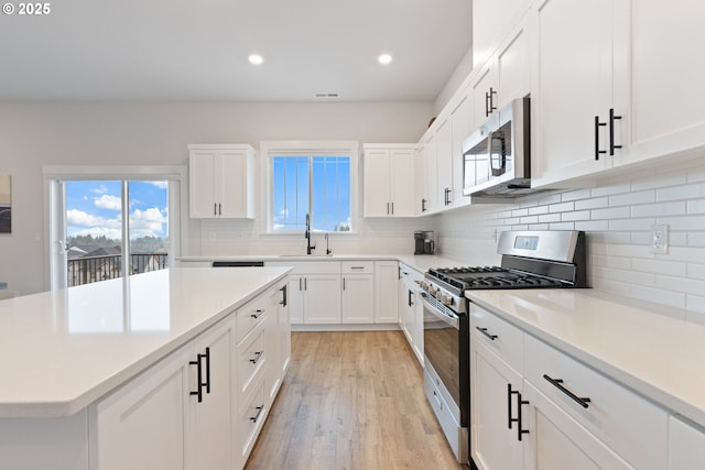 16679 SW Darwin Loop, Portland, OR 97224 - kitchen featuring appliances with stainless steel finishes, a sink, light wood finished floors, recessed lighting, and backsplash